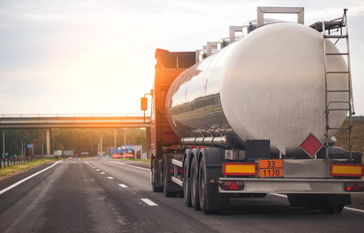 LKW mit Tankauflieger transportiert gefährliche Flüssigkeit auf der Autobahn bei Sonnenuntergang
